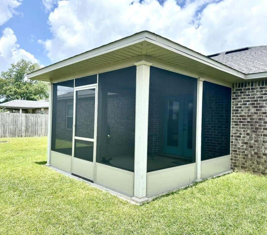 Enclosed screened room addition attached to a brick home, providing a shaded outdoor living space.
